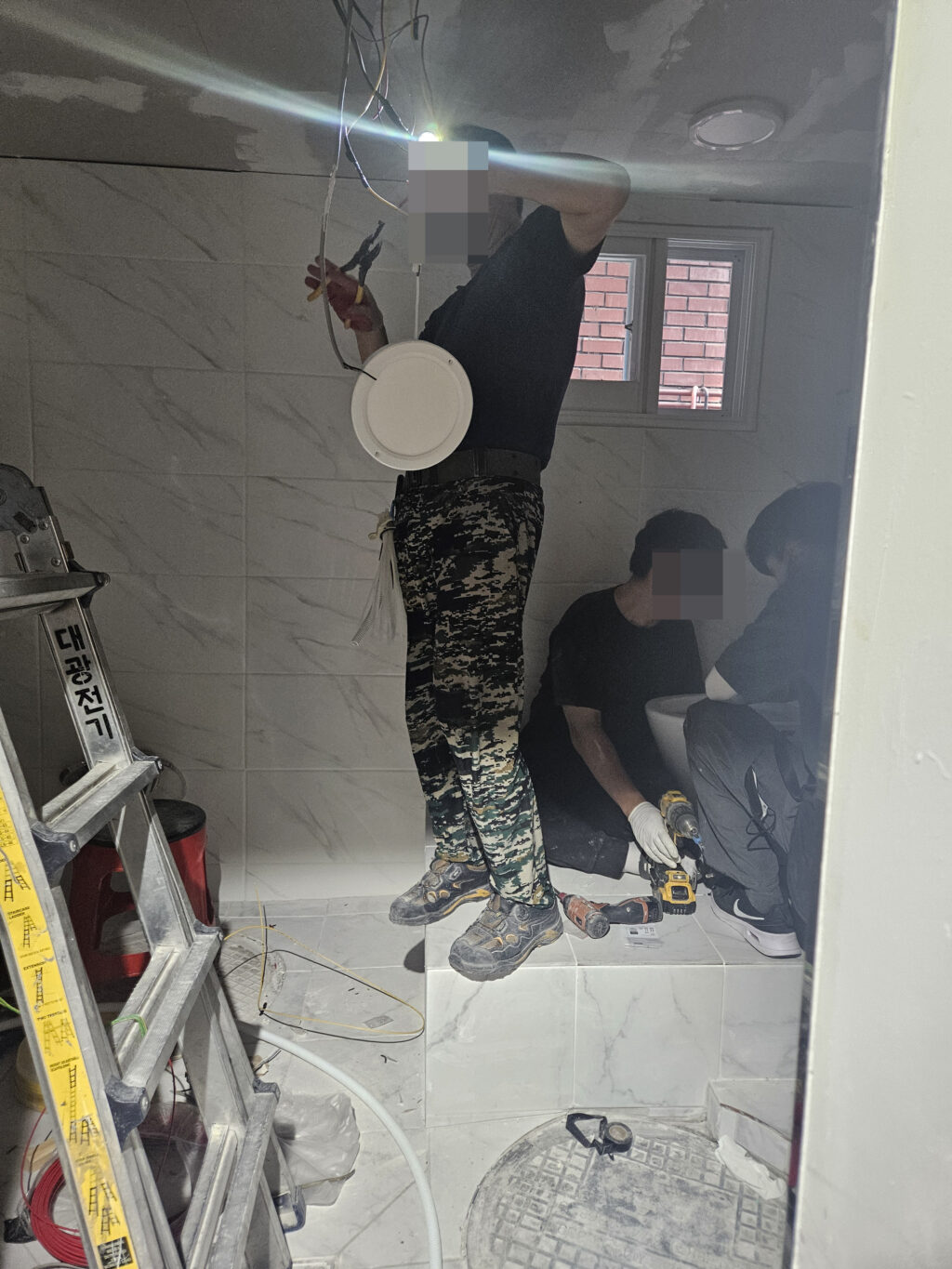 좁은 공간의 화장실에서 여러 공정들이 뒤엉켜 작업하는 모습